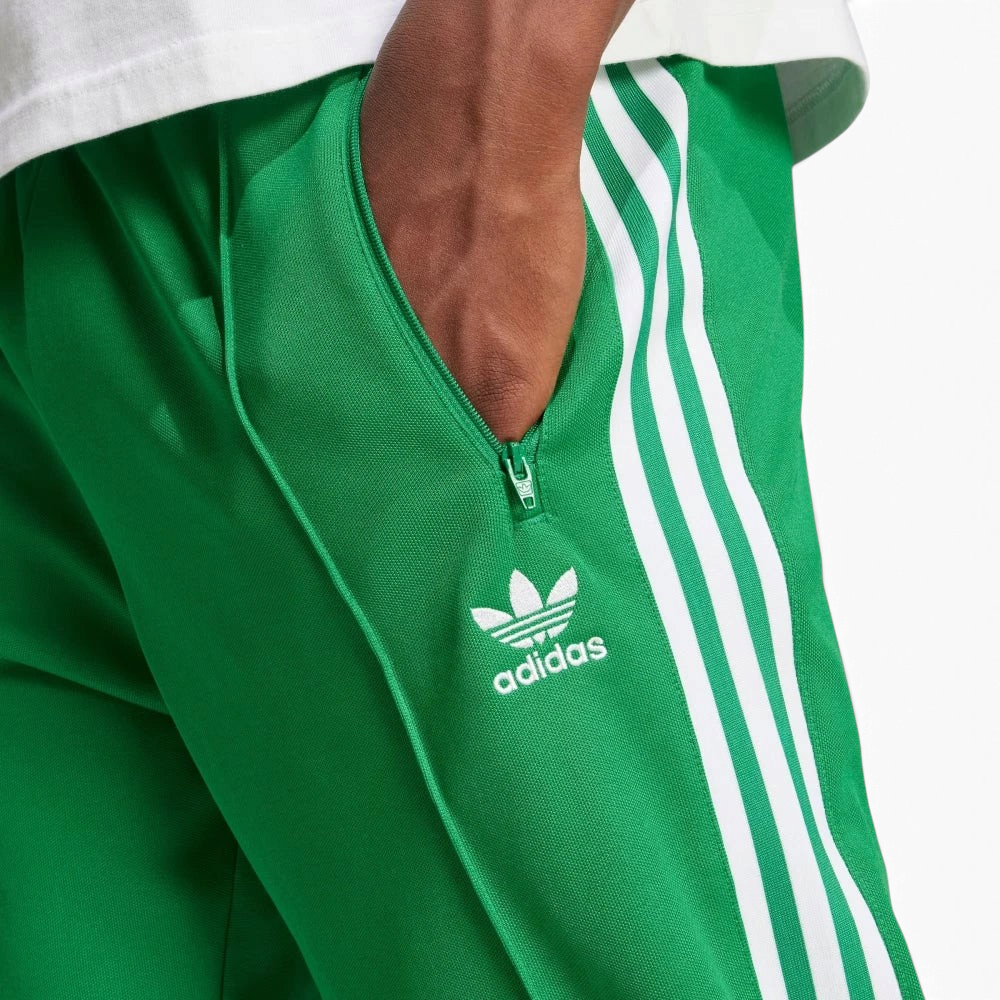 Emphasising the sharp visual contrast of the premium embroidered white Trefoil logo standing proud against the rich green fabric backdrop.