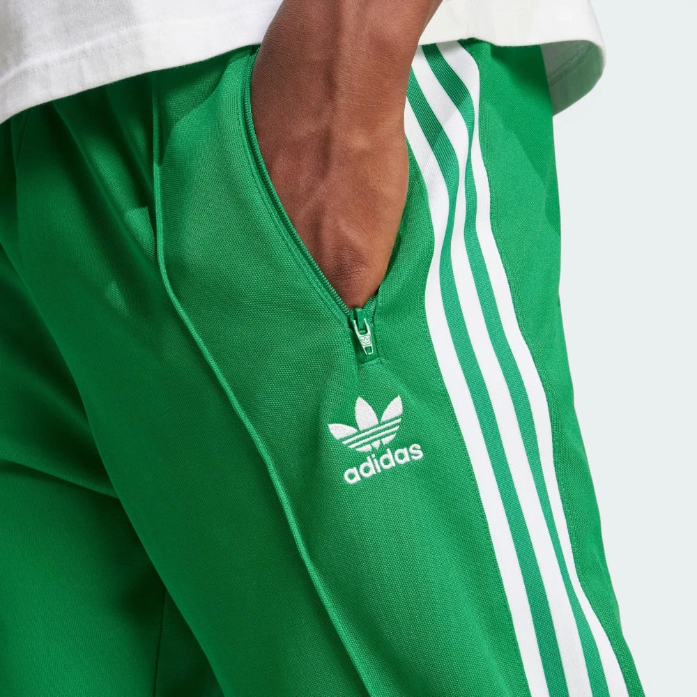 Emphasising the sharp visual contrast of the premium embroidered white Trefoil logo standing proud against the rich green fabric backdrop.
