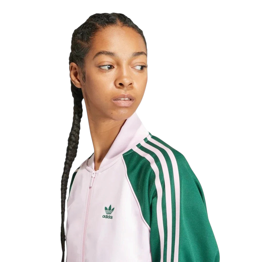 Close-up zoom on the fabric of the Adidas Adicolor Classics Loose Superstar Track Jacket in pink, showing the smooth interlock texture and the embroidered Trefoil logo detail on the chest.