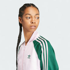Close-up zoom on the fabric of the Adidas Adicolor Classics Loose Superstar Track Jacket in pink, showing the smooth interlock texture and the embroidered Trefoil logo detail on the chest.