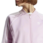 Close-up zoom on the fabric of the Adidas Adicolor Classics Superstar Track Jacket in pink, showing the soft texture and the embroidered Adidas Trefoil logo detail on the chest.