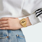 Adidas Edition One Watch in gold metallic on a person's wrist, showcasing its elegant fit and bold Trefoil design.