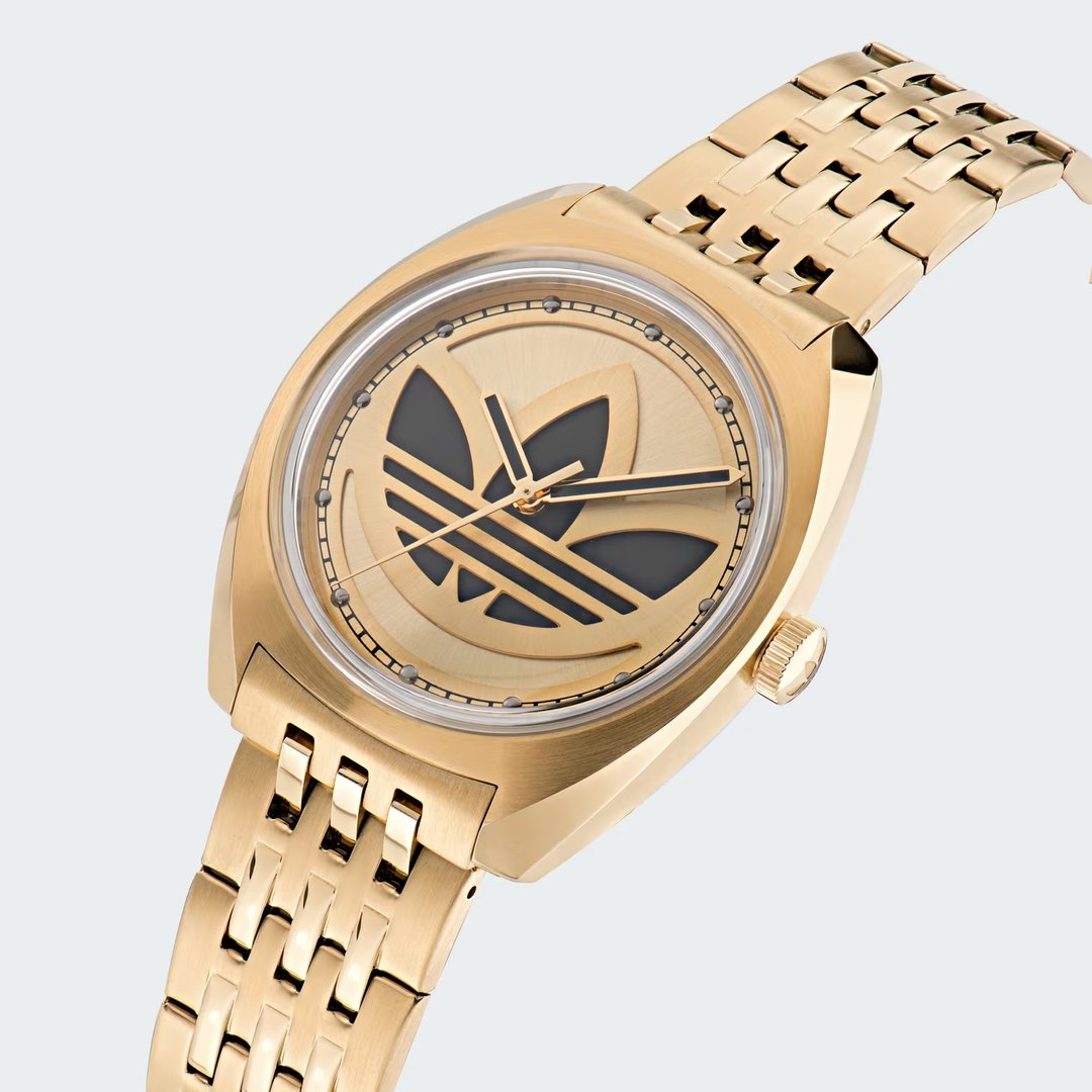 Detailed zoom on the watch face of the Adidas Edition One Watch, highlighting the precise cut-through Trefoil logo and the reflective domed lens.