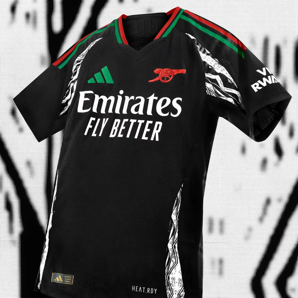 Studio product shot of the Arsenal 24/25 away authentic jersey in black, highlighting the flat-knit V-neck collar in Pan-African flag colours, white Emirates Fly Better sponsor logo, green adidas logo, and intricate side panel graphics.