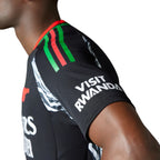 Macro focus on the shoulder seam displaying the red, green, and black 3-Stripes alongside the "Visit Rwanda" sleeve sponsor branding.