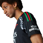 Macro close-up focus on the shoulder seam displaying the red, green, and black 3-Stripes alongside the "Visit Rwanda" sleeve sponsor branding.