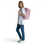 Woman holding a pink backpack against a plain background