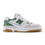 Displays the full lateral silhouette featuring the crisp white full-grain leather upper, perforated midfoot panels, Brighton Grey suede toe bumper, puffed two-tone 'N' logo with Nori green border, stitched white midsole, and rubber outsole rim.