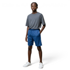 Person wearing a gray t-shirt and blue shorts standing against a plain background