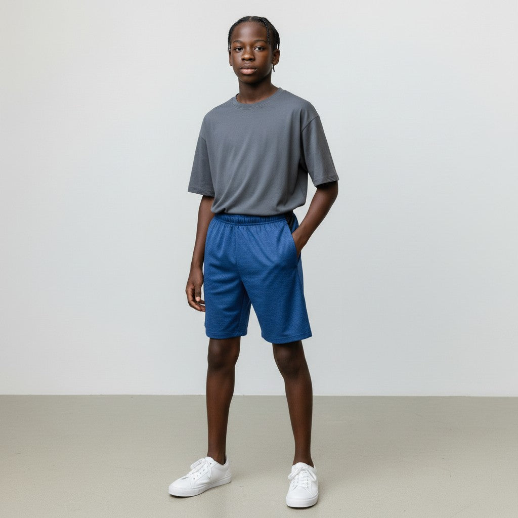 Person wearing a gray t-shirt and blue shorts standing against a plain background