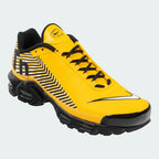 Angled view of two Nike Air Max Plus TN SE Juniors' trainers in yellow, white, and black, side by side, showcasing their bold design and layered construction.