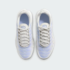 Top-down view of a pair of Nike Air Max Plus Juniors' Girls' trainers in blue, white, and grey, highlighting their iconic silhouette and lace-up closure.