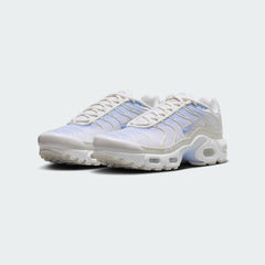 Angled view of two Nike Air Max Plus Juniors' Girls' trainers in psychic blue, white, and phantom, side by side, showcasing their bold design and layered construction.