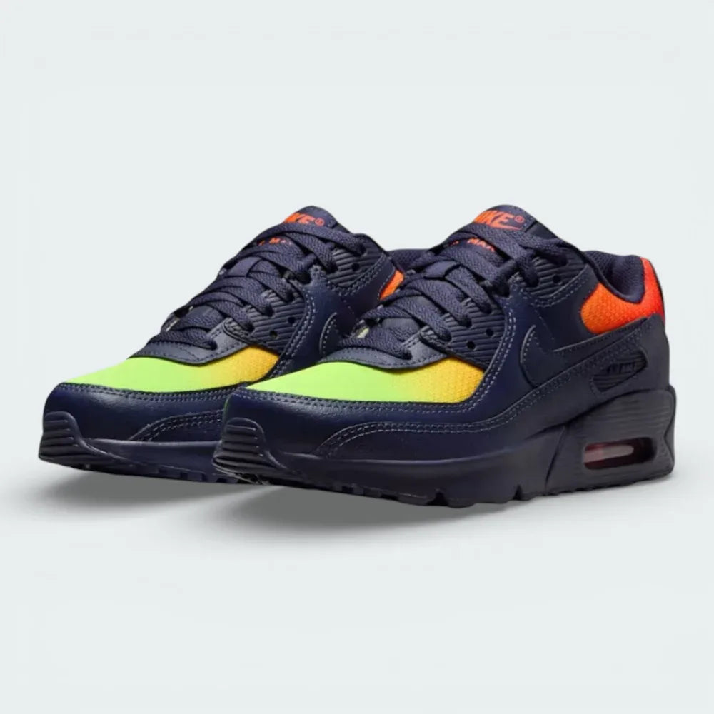 Angled shot of both Nike Air Max 90 trainers side by side, showcasing the layered leather design and the striking contrast of the neon yellow highlights.
