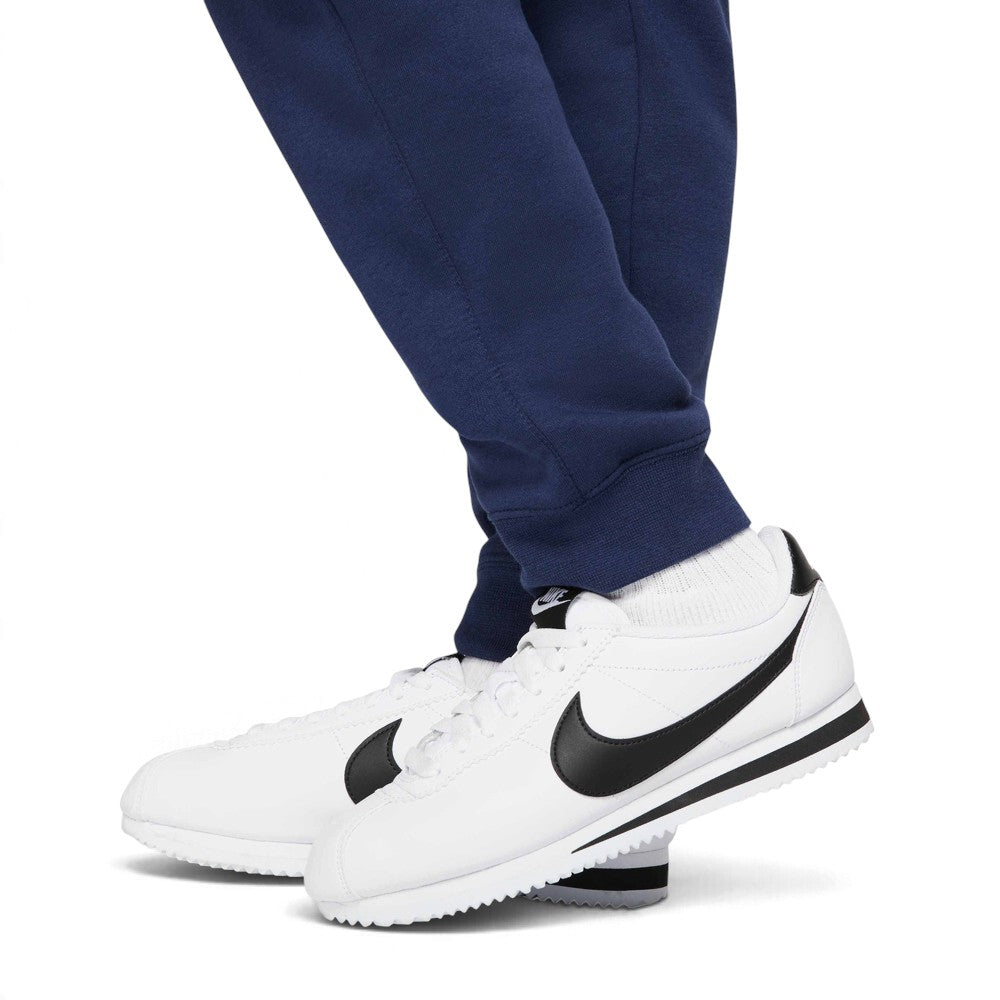 Macro focus on the ribbed ankle cuffs and white trainers, demonstrating how the trousers taper to showcase footwear.