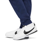 Macro focus on the ribbed ankle cuffs and white trainers, demonstrating how the trousers taper to showcase footwear.