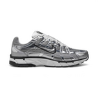Highlights the high-velocity sweep of the black-outlined metallic silver Nike Swoosh, showing the breathable metallic grey mesh base, complex grid of chrome vertical and horizontal overlays, and white foam midsole.
