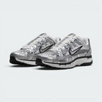 Emphasising the aggressive three-quarter Y2K stance of the trainers and the striking sheen of the metallic silver uppers sitting cleanly above the dual-tone midsoles.
