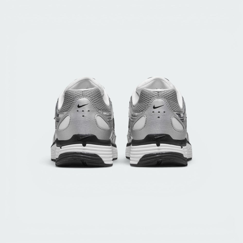 Focuses on the rear profile, highlighting the silver synthetic heel counter with ventilation perforations, micro-Swoosh logos, and the wide white-and-black foam stack below.