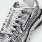 Details the micro-precision of the metallic mesh toe box, showing the chrome toe bumper, white laces, mini black Swoosh on the toe tip, and the silver "NIKE" tongue badge.