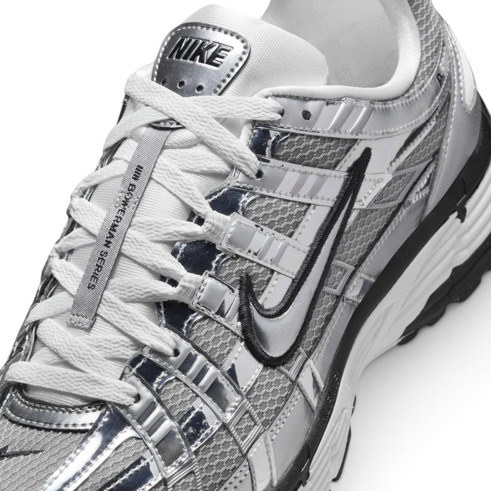 Details the micro-precision of the metallic mesh toe box, showing the chrome toe bumper, white laces, mini black Swoosh on the toe tip, and the silver "NIKE" tongue badge.