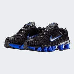 Angled view of two Nike Shox TL men's sneakers in black and metallic silver, side by side, showcasing their bold, tech-inspired design.
