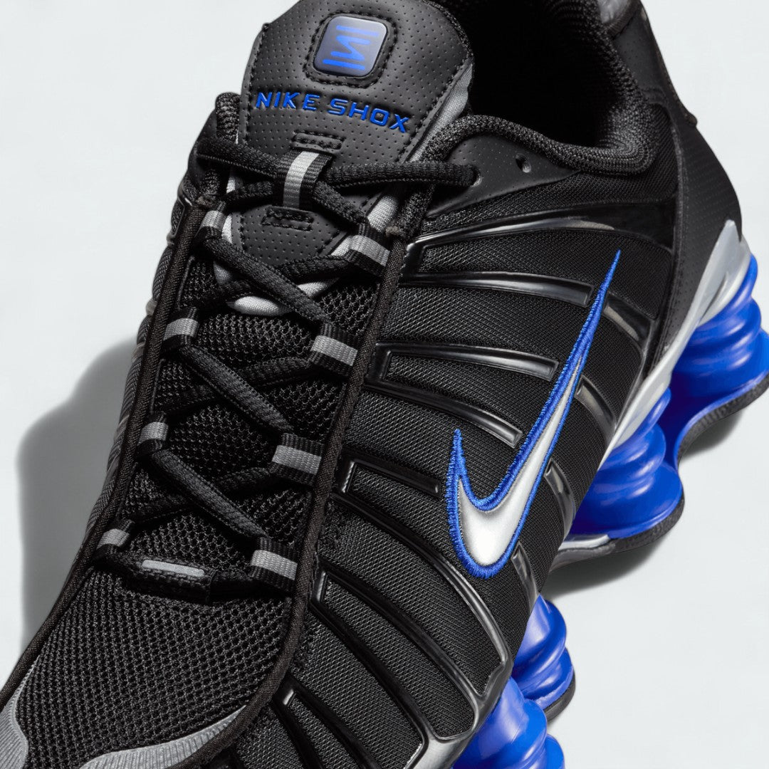 Close-up zoom on the front of the Nike Shox TL men's sneakers, showing the woven upper texture, lace-up system, and protective toe overlay.