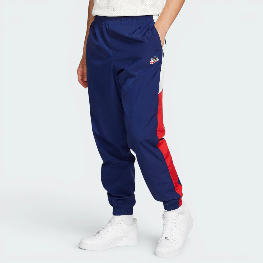 Highlights the high-velocity sweep of the Court Blue panelling tracking down the leg, showing the professional, matte texture of the Sail woven fabric and the clean integration of the zippered side pocket. Main image