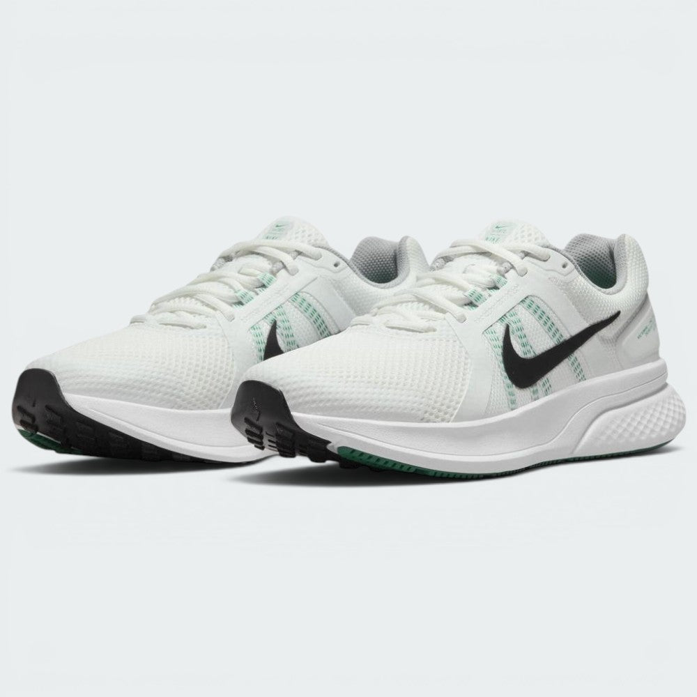 Emphasising the low-cut, athletic stance of the road runners, highlighting the contrast between the crisp white uppers, dark Swooshes, green midfoot strap accents, and green rubber outsole forefoot pods.