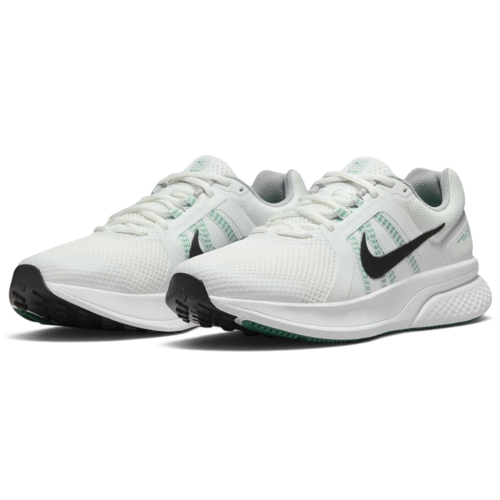 Emphasising the low-cut, athletic stance of the road runners, highlighting the contrast between the crisp white uppers, dark Swooshes, green midfoot strap accents, and green rubber outsole forefoot pods.