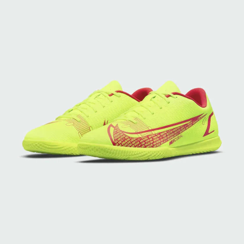 Angled view of two Nike Mercurial Vapor 14 Club IC men's indoor football boots, side by side, displaying their dynamic volt/black/crimson design.