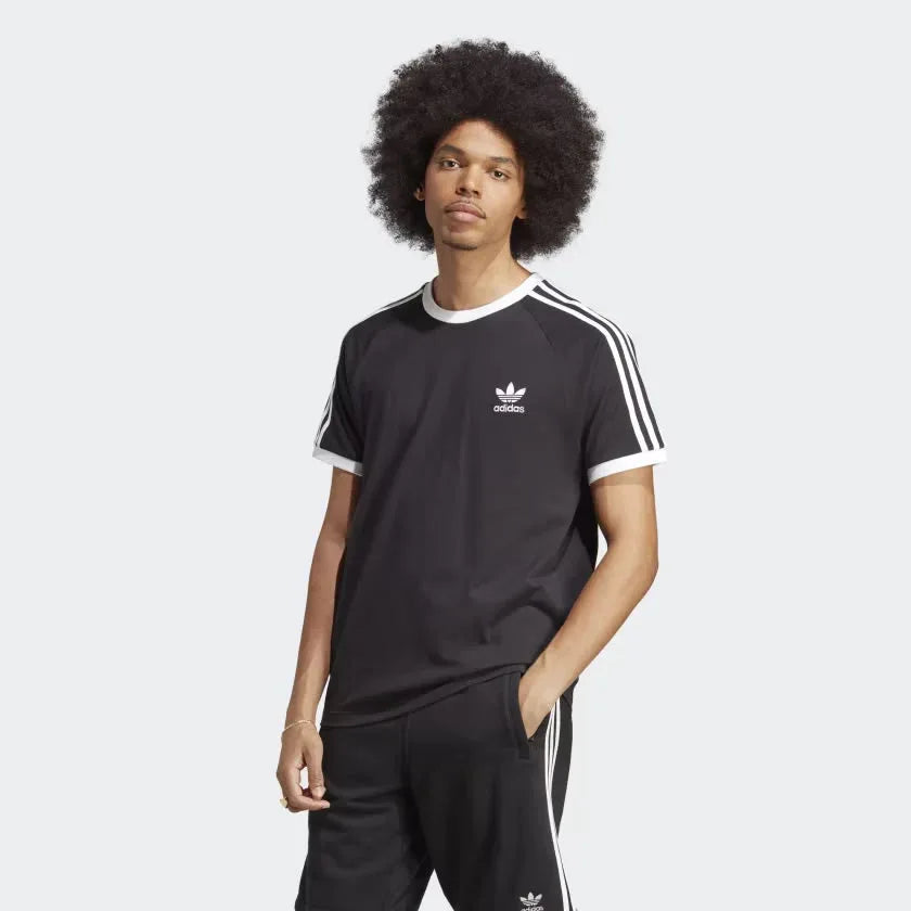A man wearing a black Adidas 3 Stripe T-Shirt with white stripes on the sleeves and a white Adidas logo on the chest.