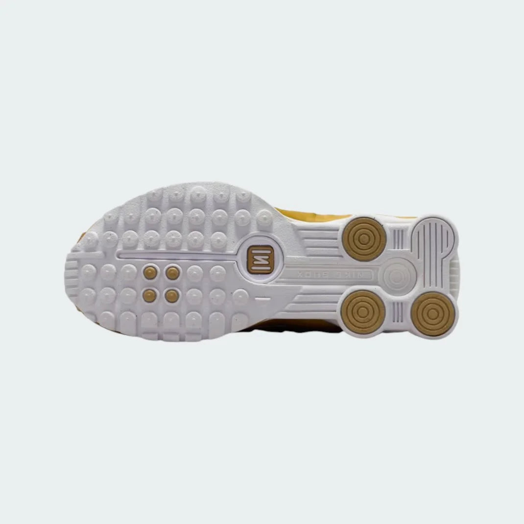 View of the outsole of the Nike Shox R4 Juniors' white/gold trainers, showing the durable rubber sole and the visible Shox columns.