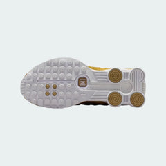 View of the outsole of the Nike Shox R4 Juniors' white/gold trainers, showing the durable rubber sole and the visible Shox columns.