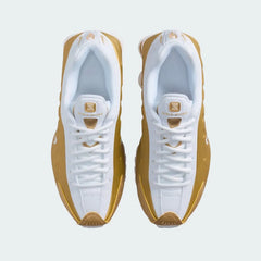 Top-down view of a pair of Nike Shox R4 Juniors' trainers in white and gold, highlighting their classic silhouette and lace-up closure.