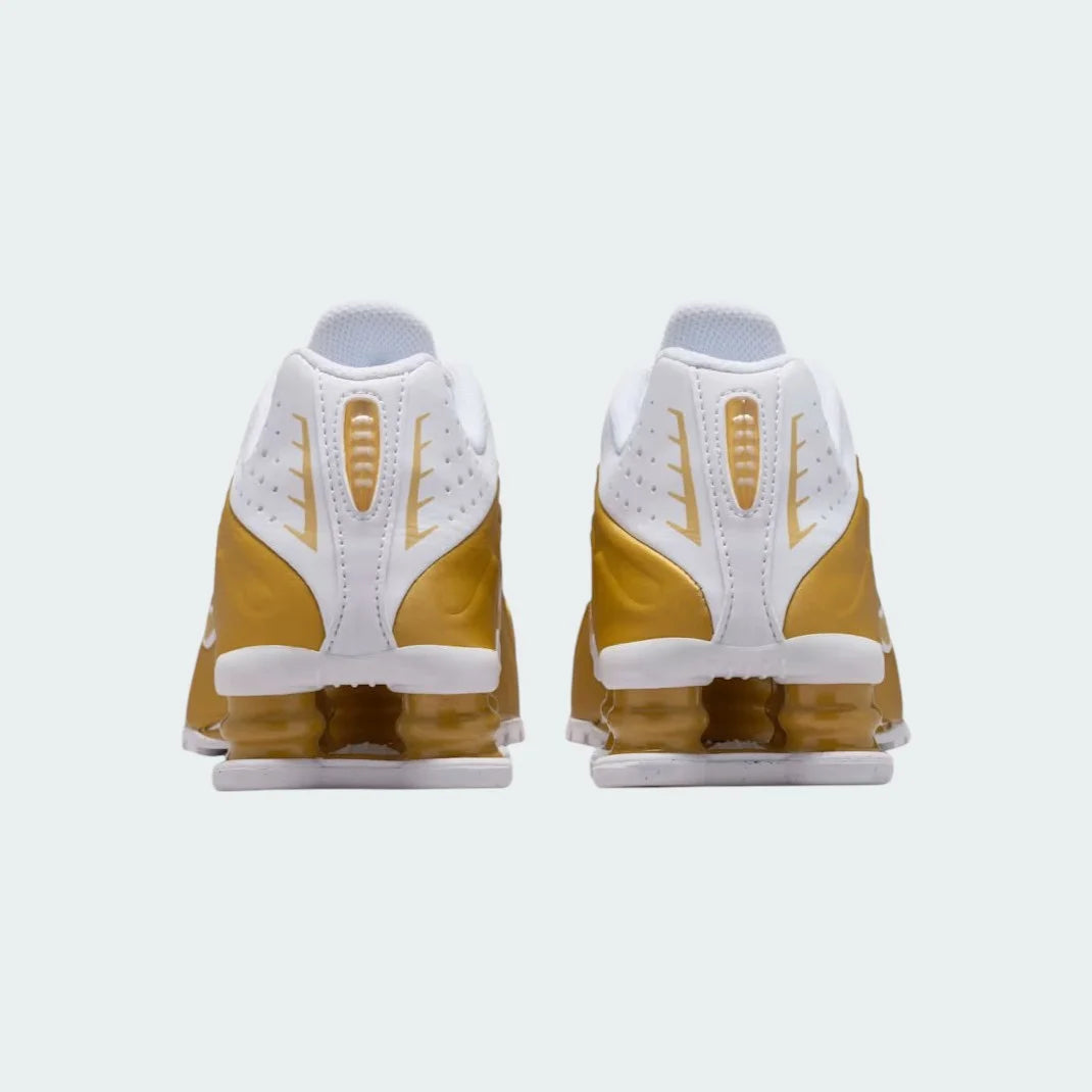 Rear view of the Nike Shox R4 Juniors' trainers, focusing on the prominent Shox columns in the heel and the gold heel counter.