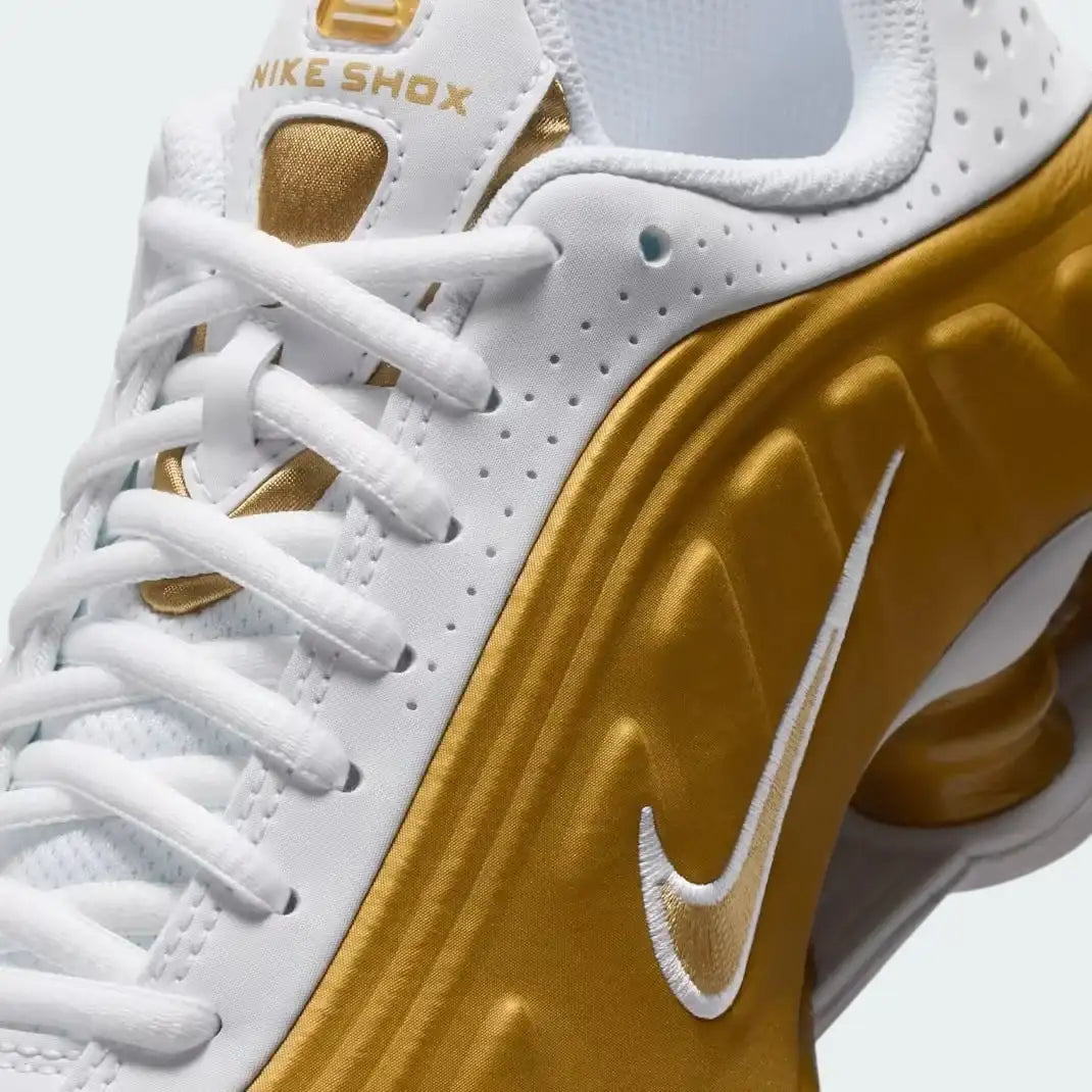 Close-up zoom on the front of the Nike Shox R4 Juniors' trainers, showing the synthetic overlays, lacing system, and perforated toe box.