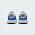 Focuses on the rear profile, highlighting the Wolf Grey leather heel tabs stamped with vibrant blue "NIKE AIR" embroidery, sitting above the wide, clean stack of the white foam midsole base.