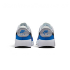 Focuses on the rear profile, highlighting the Wolf Grey leather heel tabs stamped with vibrant blue "NIKE AIR" embroidery, sitting above the wide, clean stack of the white foam midsole base.