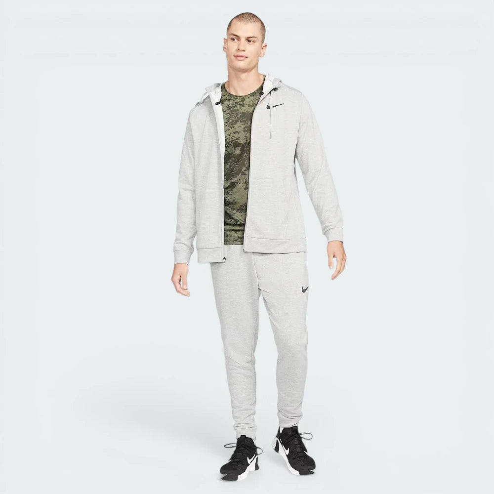 Man wearing a gray tracksuit with a Nike logo on a white background