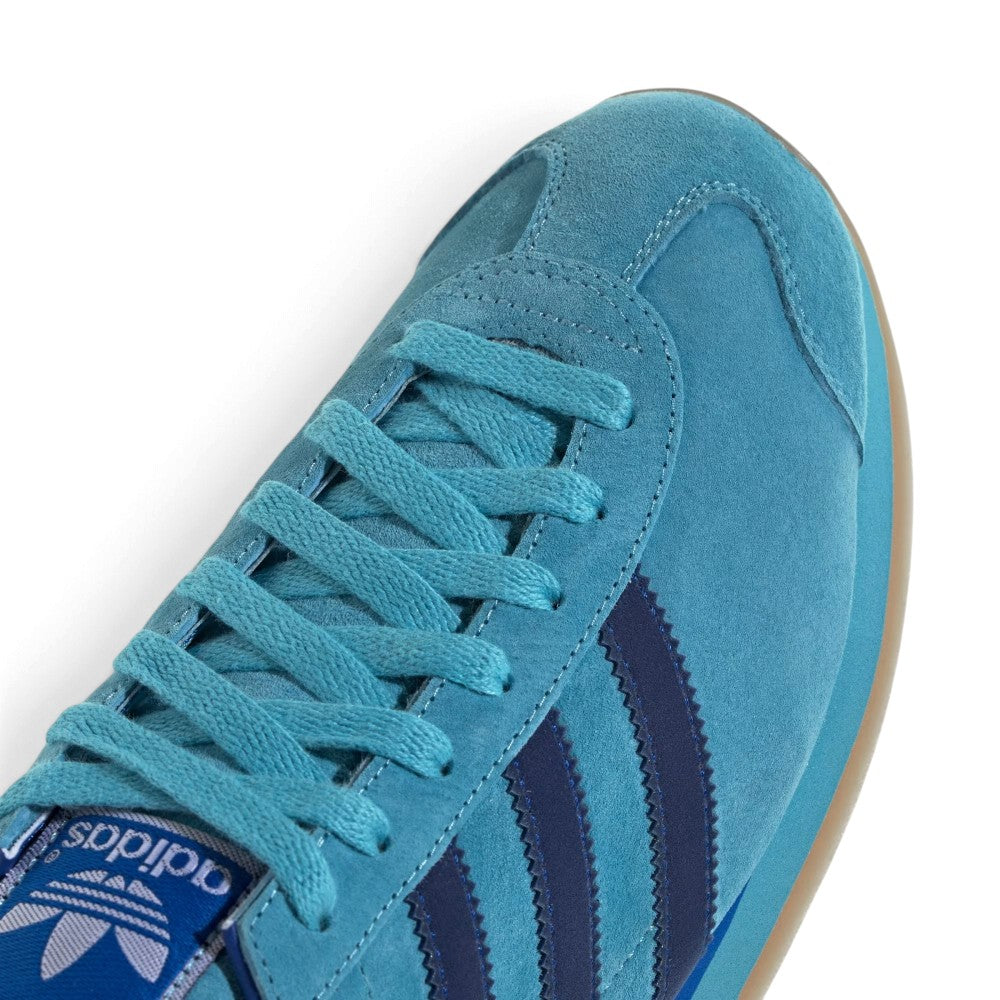 Zoom Looking at the Outsole and Midsole: Detailed close-up angle capturing the textured gum rubber heel wrap, blue midsole wedge, and gold foil side lettering.   