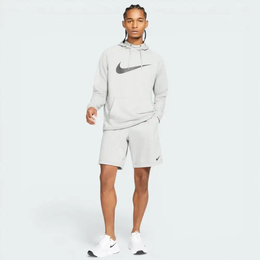 Person wearing a Nike hoodie and shorts on a white background