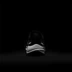 Demonstrates high-intensity night-time safety visibility, highlighting the bright dual reflective horizontal bars illuminated on the heel counter against a pitch-black background.