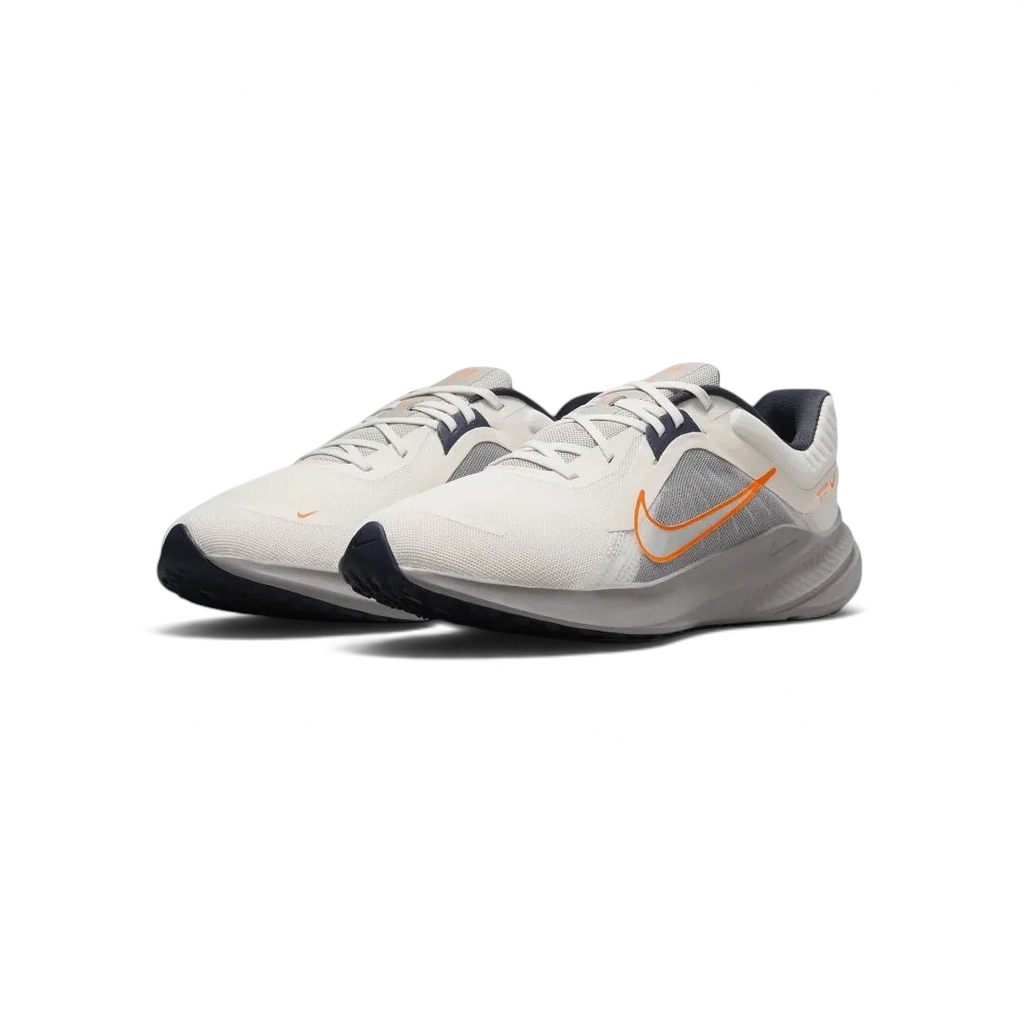 Angled view of two Nike Quest 5 Men's running shoes in sail with blue and orange accents, side by side, showcasing their lightweight design.