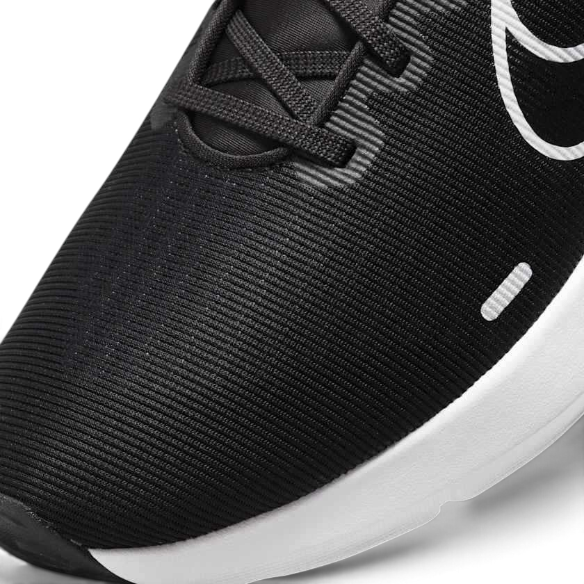 Close-up zoom on the front of the Nike Downshifter 12 Men's black training shoes, showing the mesh upper texture, lacing system, and supportive midfoot band.