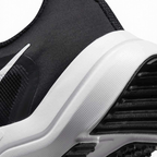 Detailed zoom on the outsole and midsole of the Nike Downshifter 12 Men's black training shoes, highlighting the soft foam cushioning and durable rubber outsole.