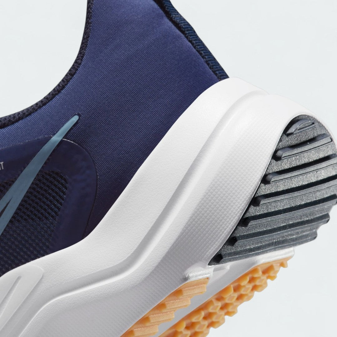 Detailed zoom on the outsole and midsole of the Nike Downshifter 12 Men's navy blue training shoes, highlighting the soft foam cushioning and durable rubber outsole.