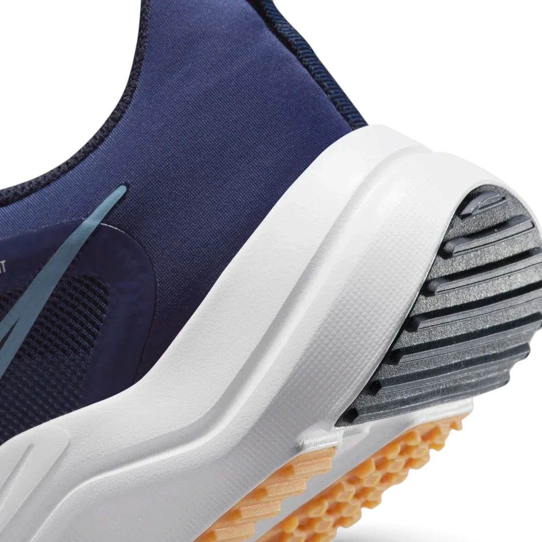 Detailed zoom on the outsole and midsole of the Nike Downshifter 12 Men's navy blue training shoes, highlighting the soft foam cushioning and durable rubber outsole.