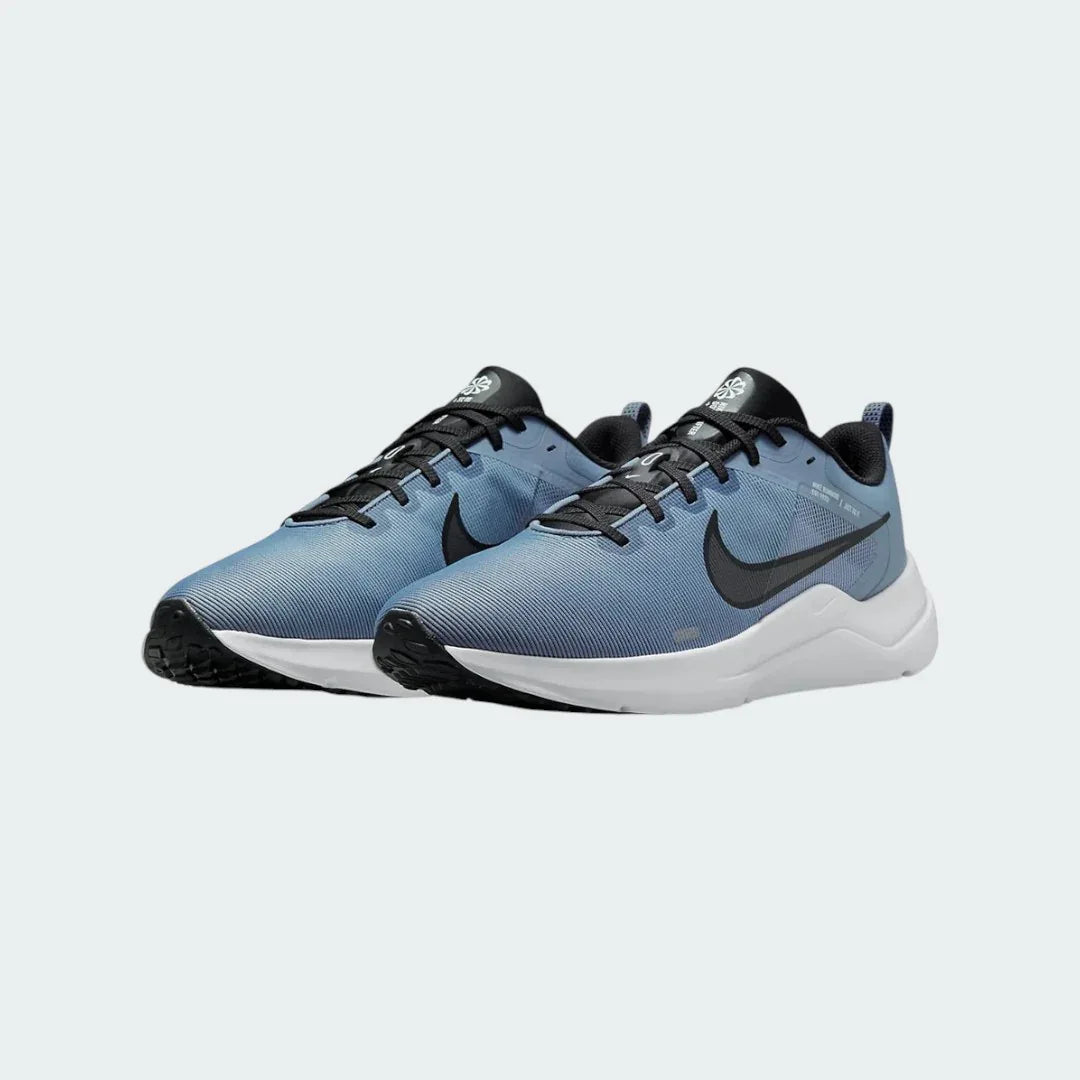 Angled view of two Nike Downshifter 12 Men's grey and black training shoes, side by side, showcasing their versatile design and cushioned profile.