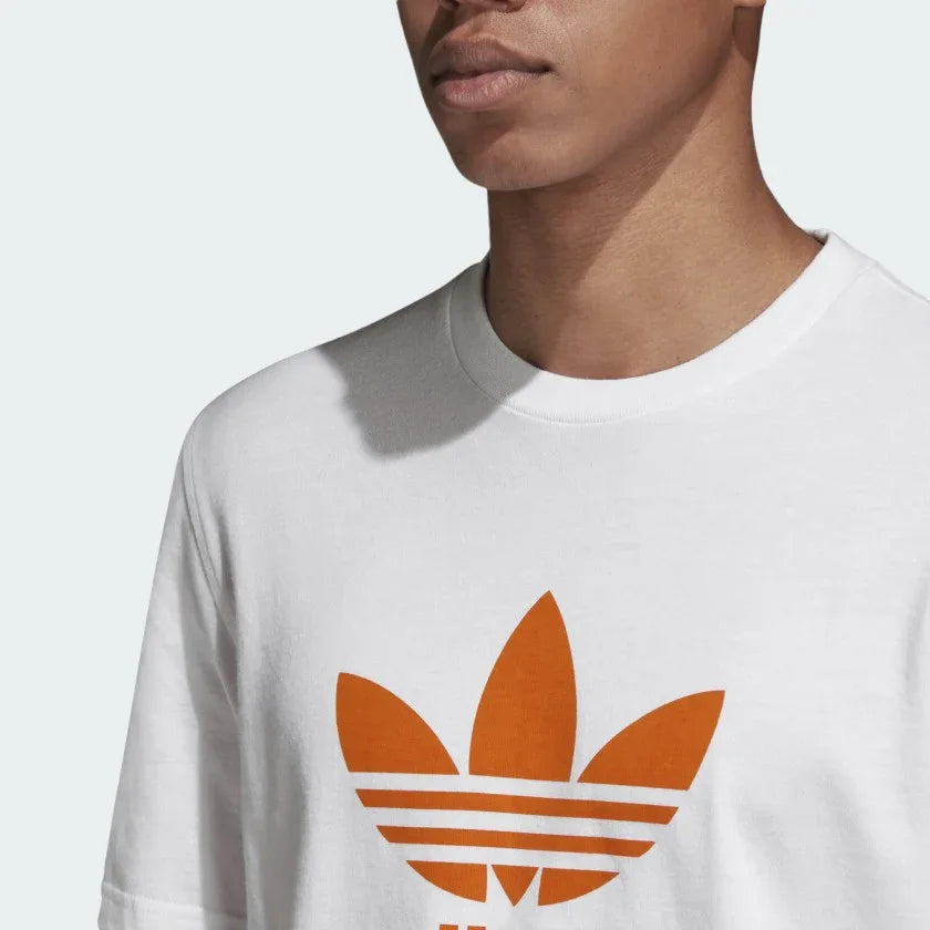 Close-up zoom on the Adidas Trefoil T-Shirt Men's in white, showing the soft cotton jersey fabric texture and the clear orange Trefoil logo print.